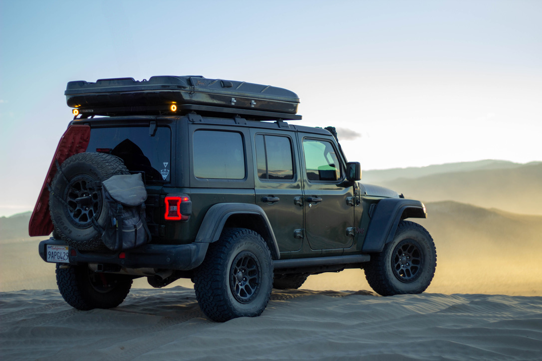 Image of a Jeep Wrangler from behind on a sandy overlook